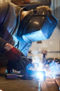 Man providing onsite welding services with a MIG welding gun to repair an item | Elite Welding & Fabrication