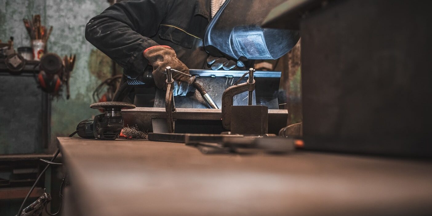 worker-in-a-welder-mask-works-in-a-workshop-for-we-2022-04-22-04-41-28-utc-min A worker in welder mask does MIG welding in a workshop.