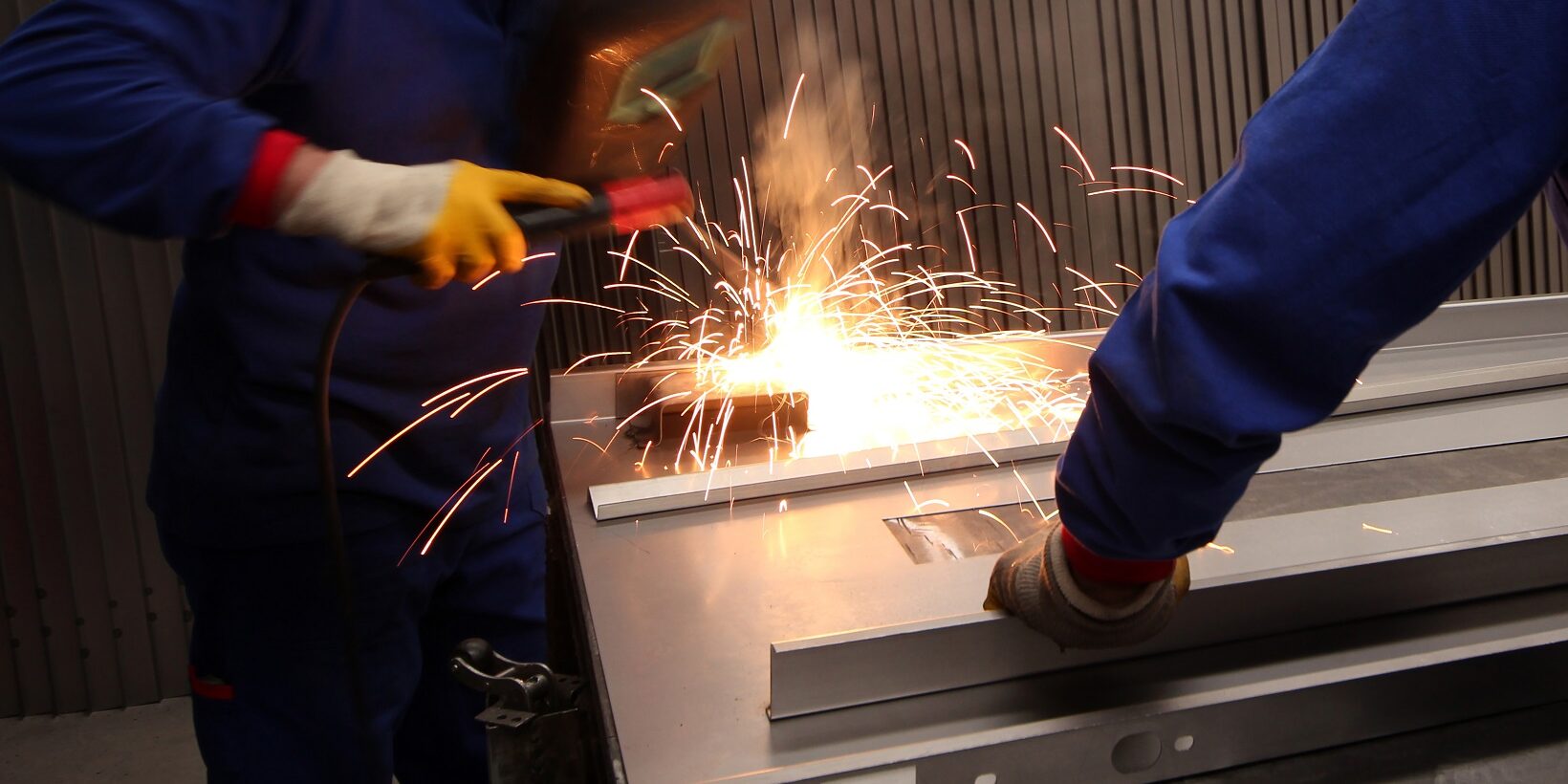 Two mature men working as welders in a metal fabrication factory. Two mature men working on component manufacturing in a metal fabrication factory.