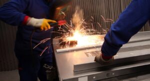 Two mature men working on component manufacturing in a metal fabrication factory.
