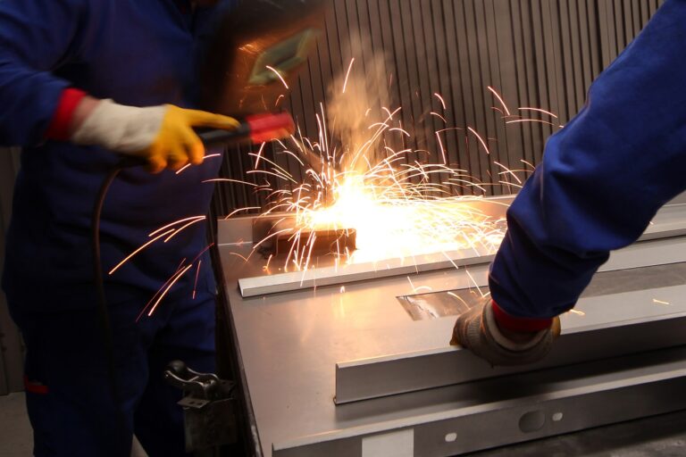 Two mature men working as welders in a metal fabrication factory. Two mature men working on component manufacturing in a metal fabrication factory.