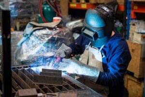A welding technician performs TIG welding on a piece of metal for a metalworking project.