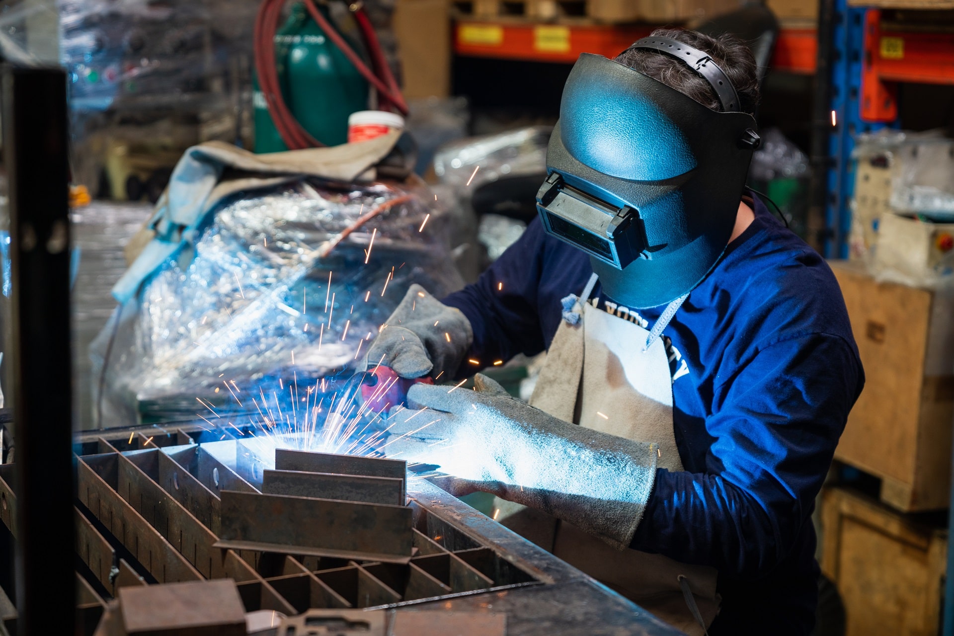 A welding technician performs TIG welding on a piece of metal for a metalworking project.