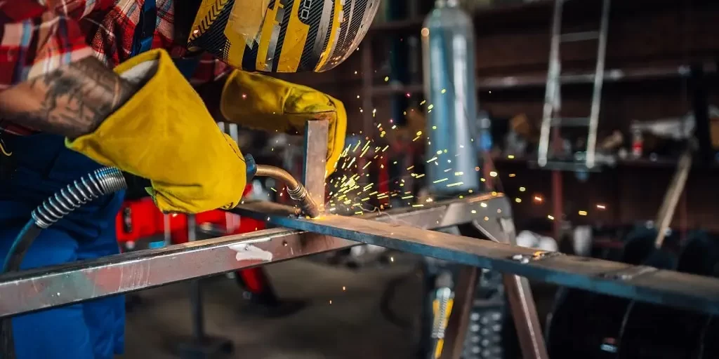 worker-in-a-workshop-welding-a-metal-construction-2023-11-27-05-26-51-utc-min Worker in a workshop welding metal for a custom steel fabrication project.