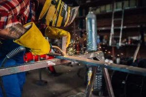 Worker in a workshop welding metal for a custom steel fabrication project.
