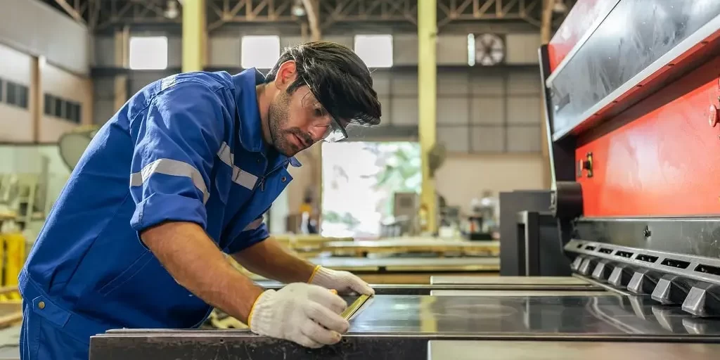 caucasian-handsome-male-industrial-worker-work-in-2023-11-27-05-15-07-utc-min Male industrial worker measures a piece of sheet metal in a manufacturing plant.