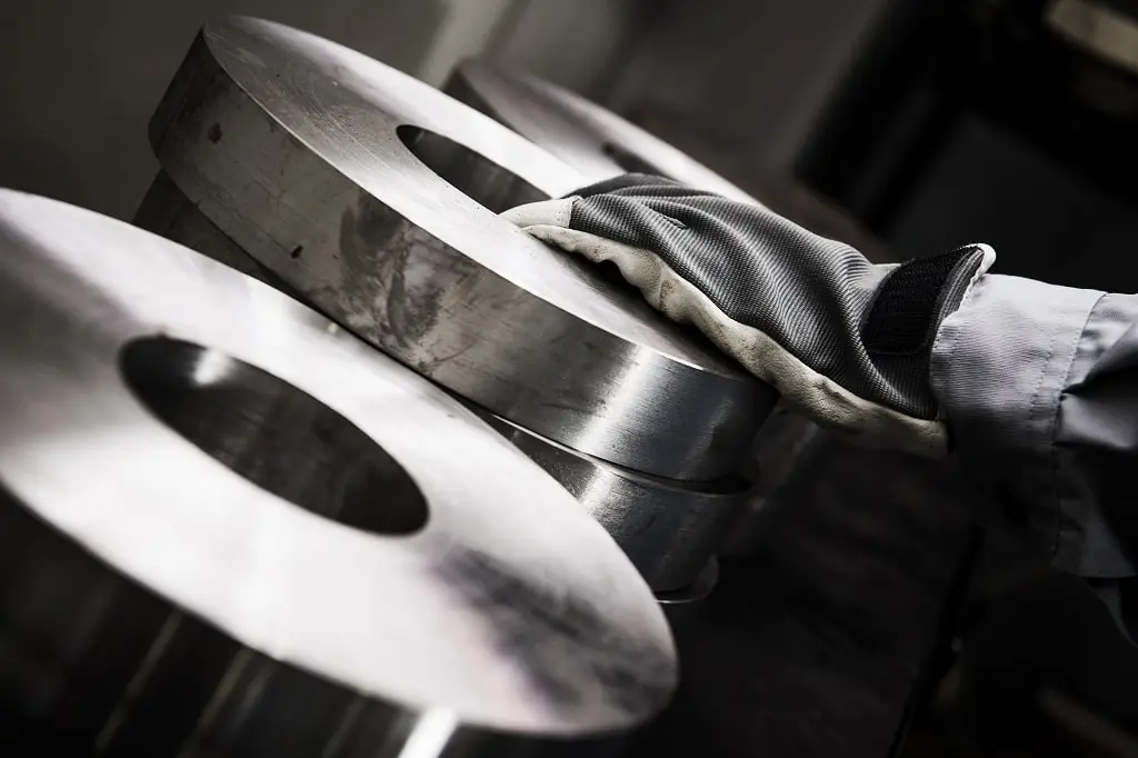 A gloved hand rests on rings of metalworking industrial material.