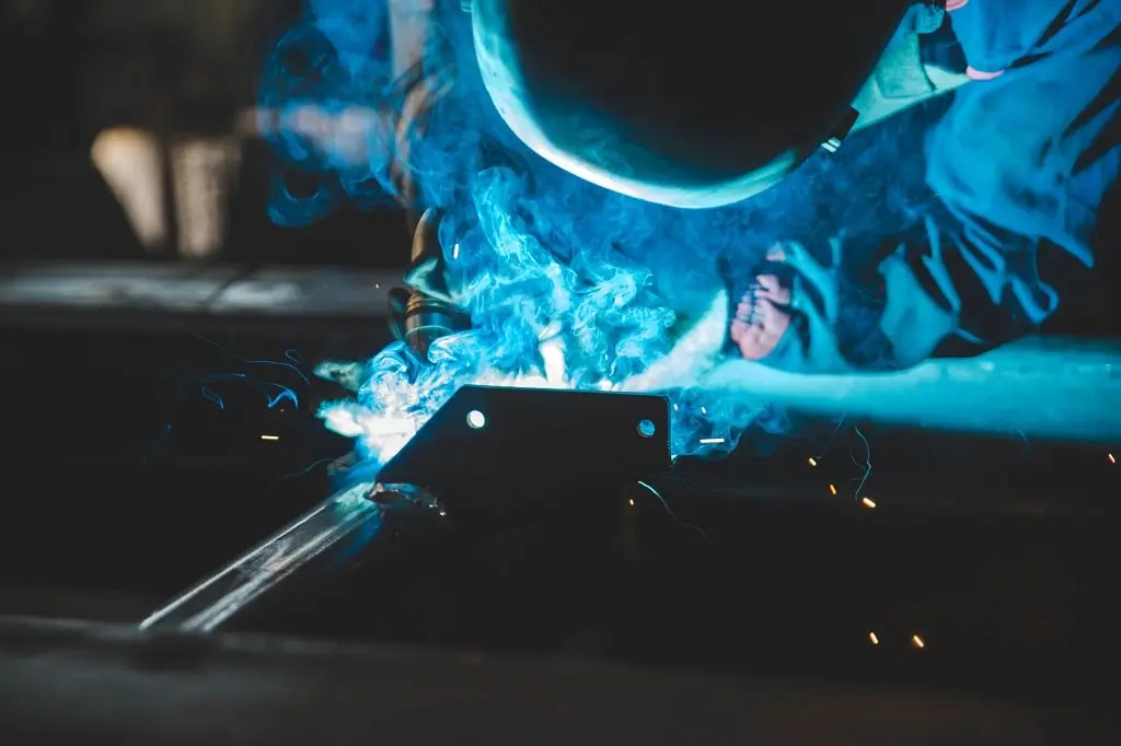 A welder is illuminated by the glow made by their MIG welding.