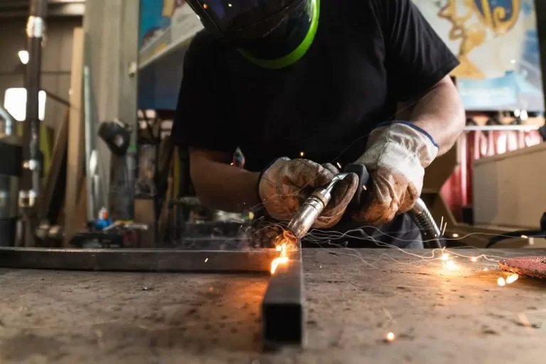 welder-in-protective-helmet-welding-metal-detail-i-2024-05-11-02-14-30-utc-min A welder in a protective helmet welds together two metal bars.