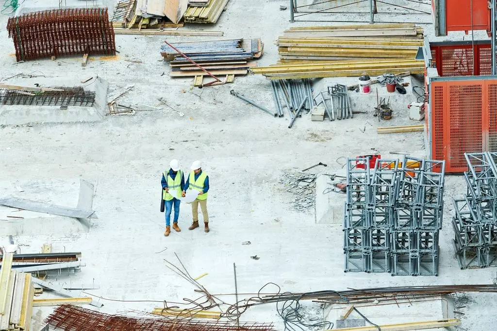 Building inspectors reading a blueprint on a construction site.