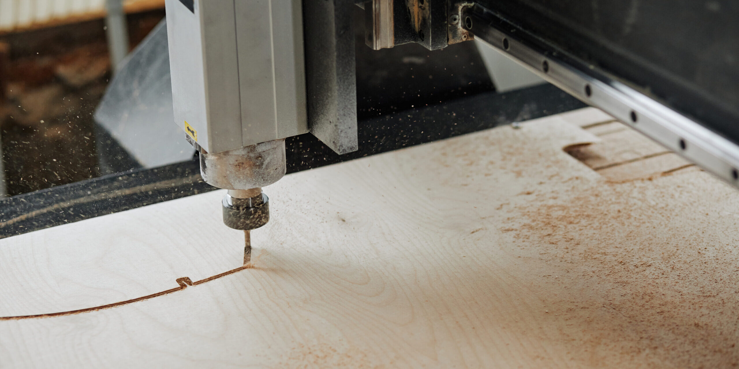 CNC Machine Cutting Wood Close up of CNC engraving machine cutting wood in automated production workshop with sawdust flakes in air, copy space
